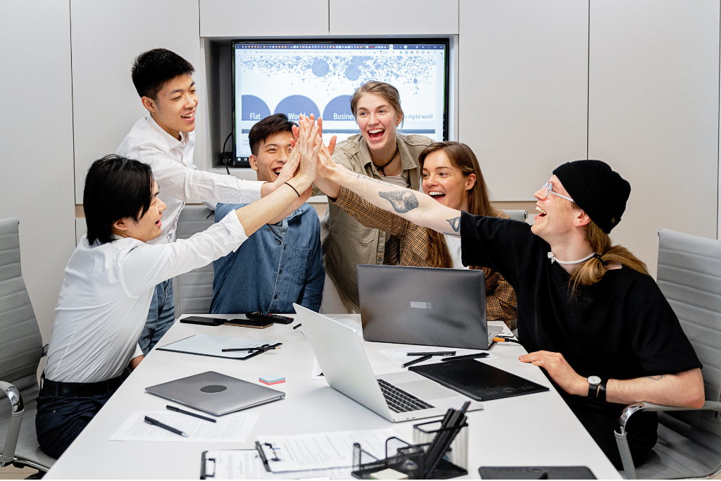 Hire dedicated offshore development team giving a high five during a meeting