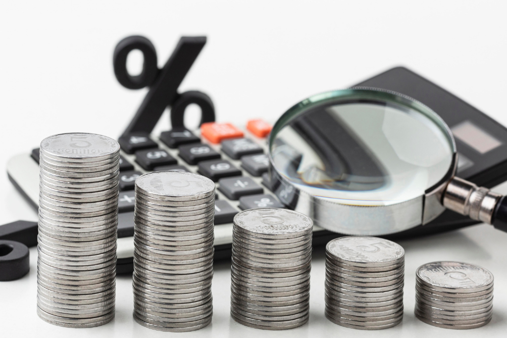 Stacks of coins with a magnifying glass and a percent sign representing hidden offshore costs